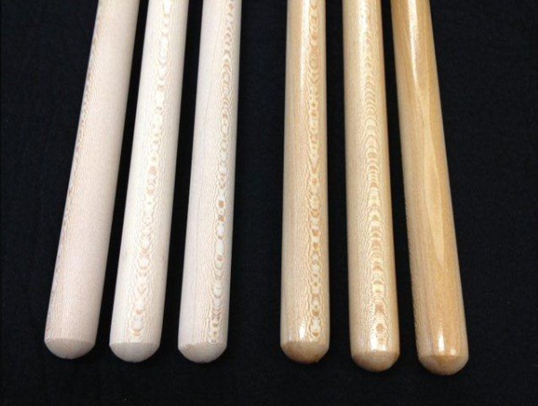 Six wooden broom and mop handles with a clear lacquer finish and tinted maple stain, available in bulk.